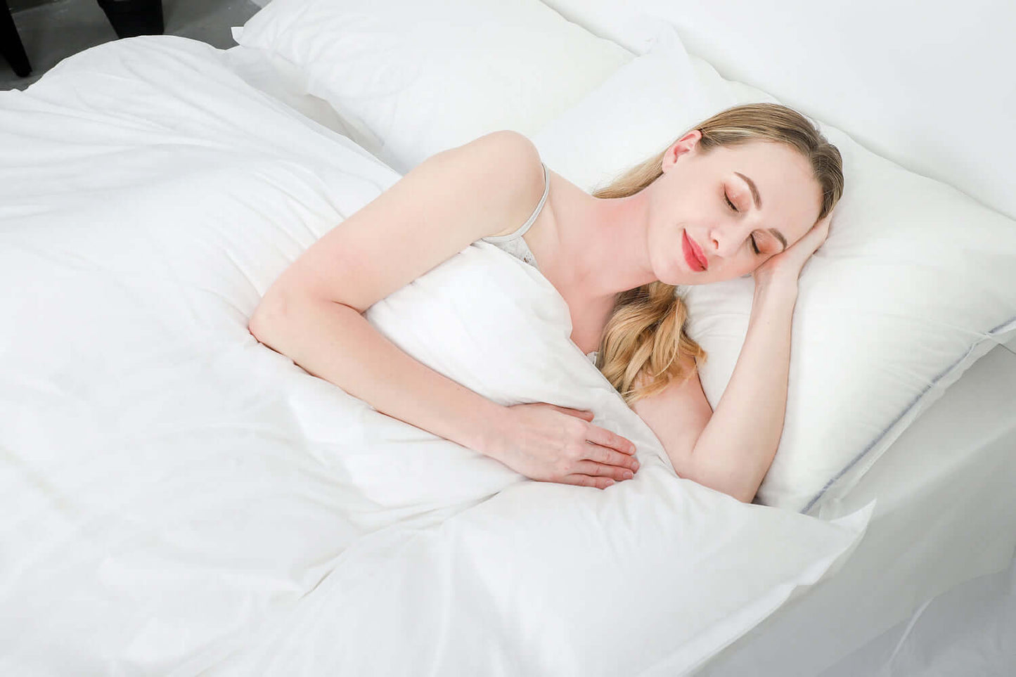 Woman sleeping peacefully in a bed with white eco-friendly disposable bed covers, ideal for travel and hospitality.