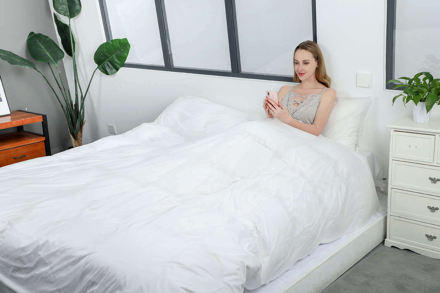 Woman relaxing on a white bed with eco-friendly disposable covers, enjoying a peaceful moment.