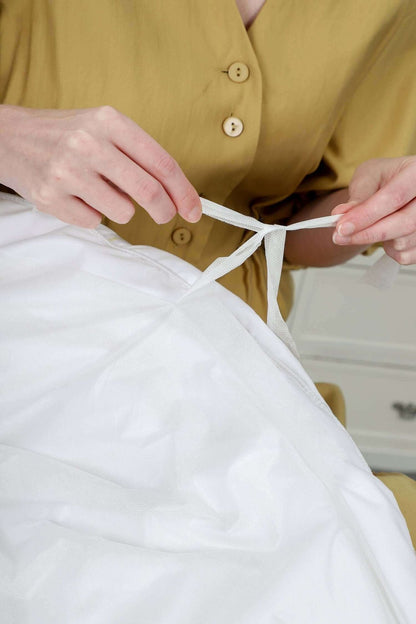 Person tying a ribbon on eco-friendly disposable bed cover, showcasing its practical design for easy use.